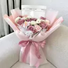 Subtle Pink Bouquet with roses, daisies, and a pink ribbon on a couch.