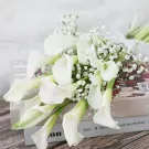 White calla lily bouquet with baby's breath on books.