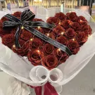 Heart-shaped bouquet of red glitter roses with fairy lights and black ribbon.