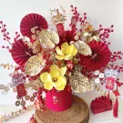 Red and gold floral arrangement with lion decorations and lucky coins.