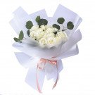 Bouquet of white roses with eucalyptus leaves, wrapped in white paper and tied with a pink ribbon.