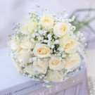 White roses and baby's breath bouquet on a light blue surface.