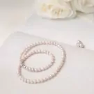 Pearlie Pearl Necklace with delicate pink pearls and a silver clasp, styled with white roses.