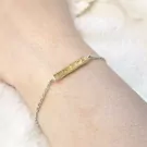 Silver chain bracelet with hammered gold bar charm on a wrist.
