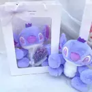 Two purple Stitch plush toys, one in a gift box with mini flowers and fairy lights.