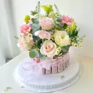 Flower arrangement with rolled banknotes around the base, adorned with pink roses, carnations, and daisies.