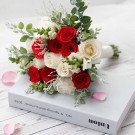 Red and white rose bridal bouquet on a book with rose petals.