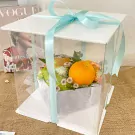 Gift box with orange, apples, flowers and magazines.