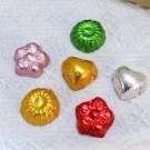 Chocolates in colorful foil wrappers, including heart shapes, on a textured white surface.