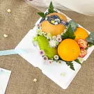 A sweet fruit box with pears, oranges, flowers, and leaves on a burlap background.