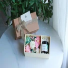 Gift box with dried flowers, soaps, and a candle, tied with twine and ribbon.