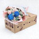 Bouquet of blue chrysanthemums and pink roses in a cardboard box, tied with ribbon.