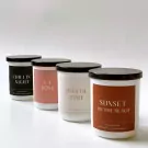 Four scented candles with black lids: "Chillin' Night", "La Rose", "Joyful Time", and "Sunset on the Beach".