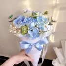Blue roses and white flowers in a cone bouquet with a blue bow.