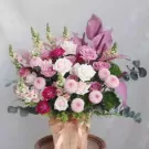 A wooden box of pink and white roses, chrysanthemums, carnations, and foliage.