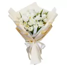 Bouquet of white tulips wrapped in cream and gold paper, tied with a white ribbon.
