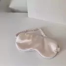 Silk sleep mask with elastic strap on a white surface.