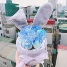 Girl in pink holding two pink bunny ear bouquets with pink roses and white ribbons.