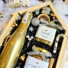 Christmas gift box with champagne, granola, cookies, and festive decorations.