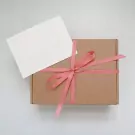 Card with pink ribbon on a gift box.