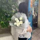 Woman in white lace top holding a bouquet of white roses.