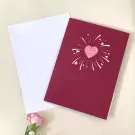 A red pop-up card with a heart and "love" on it next to a white envelope.