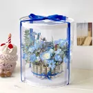 A clear box of blue flowers with money rolled around the base.