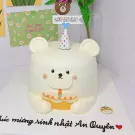 A white bear-shaped cake with a birthday candle and a "Happy Birthday!" topper.