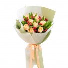 Peach roses and red berries in a bouquet with light green and white wrapping, tied with a peach ribbon.