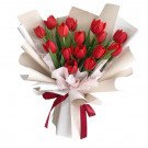 Bouquet of 15 red tulips in beige and white wrapping, tied with red ribbons.