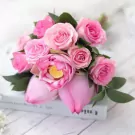 Pink lotus and rose bouquet with green leaves, resting on a book.