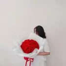 Woman in white holding a large bouquet of red roses.