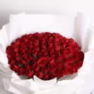 A large bouquet of 99 vibrant red roses in white paper wrapping.