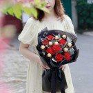 Woman in yellow dress holding a bouquet of red carnations and Ferrero Rocher chocolates.