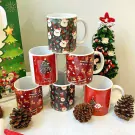 Christmas mugs with festive designs and a mini Christmas tree.