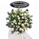 White roses and lilies funeral wreath with a memorial plaque.