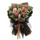 A bouquet of brown peony chrysanthemums with baby's breath and eucalyptus leaves, wrapped in black and brown paper, tied with a ribbon.