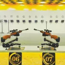 Two rifles on stands at a shooting range with numbered targets in the background.