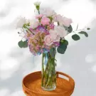 Pastel floral arrangement in a glass vase with roses, hydrangeas, and carnations.