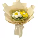 Bouquet of yellow and white ping pong chrysanthemums with daisy-like flowers, wrapped in beige paper with a ribbon.