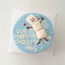 Blue cake with a marshmallow snowman angel, "Our Happy Xmas" text, and white dots.