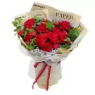 Red roses and carnations with greenery, wrapped in paper and ribbon.