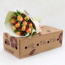 Peach roses and red berries in a bouquet on a cardboard box.