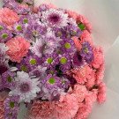 A bouquet of pink and purple carnations, violets, and chrysanthemums.
