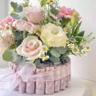 Money cake adorned with pink and cream roses, daisies, and greenery.