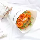 Bouquet of orange Spirit roses with greenery, wrapped in paper with sheet music design.