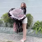 Woman in white shorts and heels holding a giant bouquet of pink baby's breath flowers.