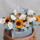 Basket of sunflowers, white daisies, and greenery.