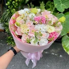 Pink and white rose bouquet with carnations, daisies, and greenery.