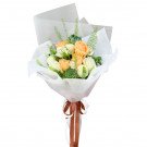 Peach and white roses with succulents and greenery in a white paper bouquet.